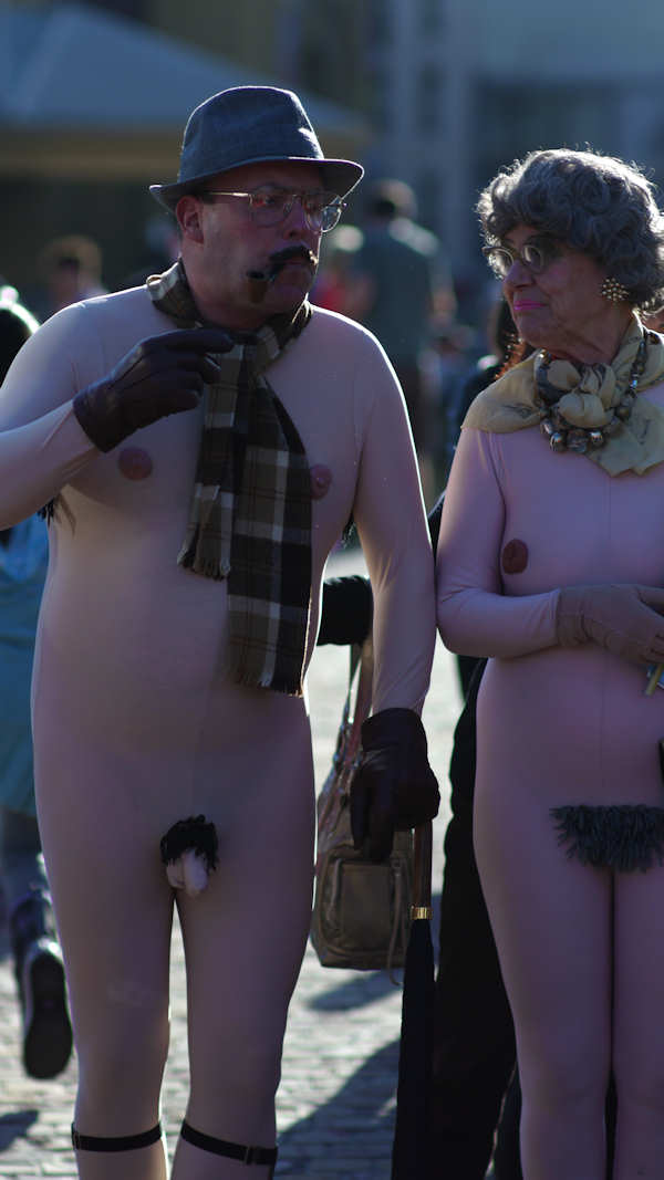 P1130195.jpg - Into the sun at f/1.4. This very unusual elderly couple with American accents were walking through Melbourne's Fed Square presumably celebrating the Comedy Festival!